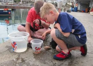 Two boys with crabbing buckets full of water, inspecting their catch