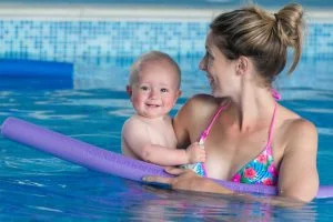 A woman and a smiling baby in a swimming pool