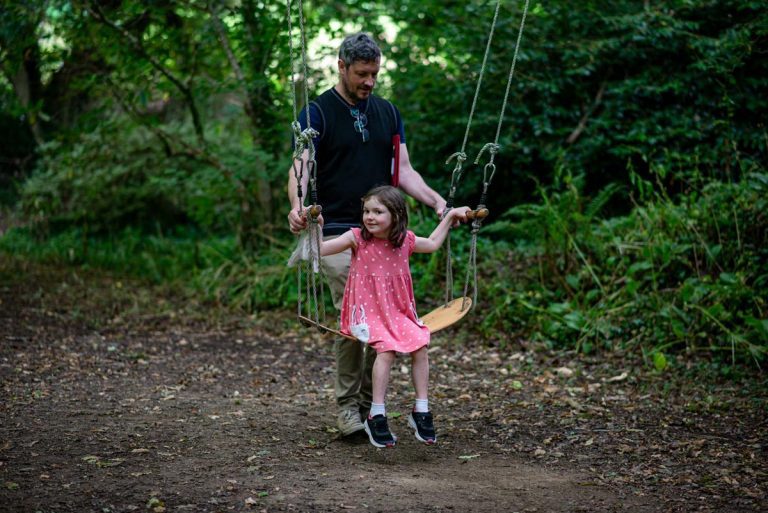 Father and daughter playing on a swing in the forest at Bosinver.