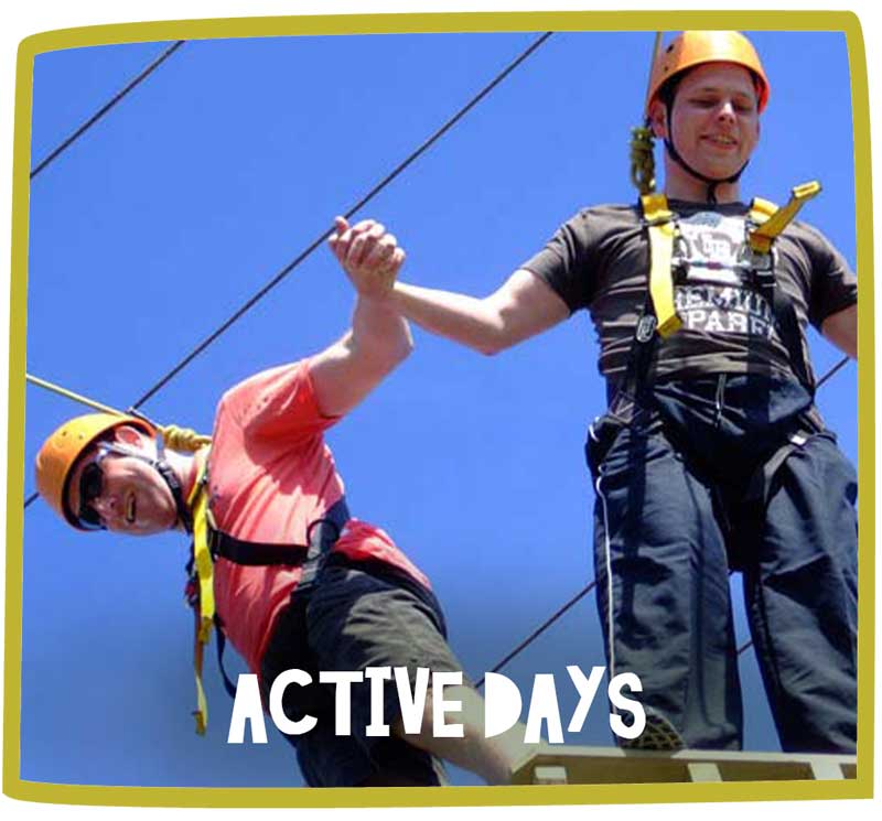 Two men taking on the high wire together at an adventure park.