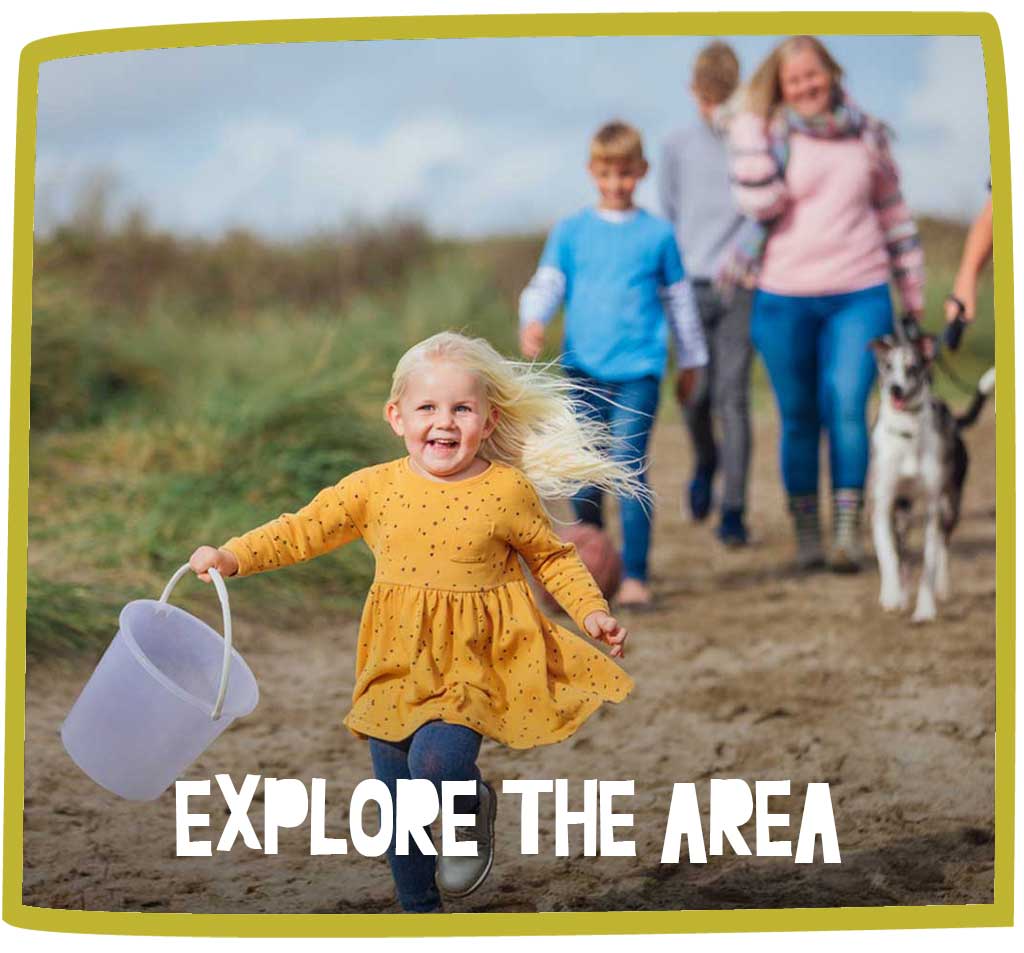Young girl with a bucket running and smiling as she explores Cornwall with her family and dog.