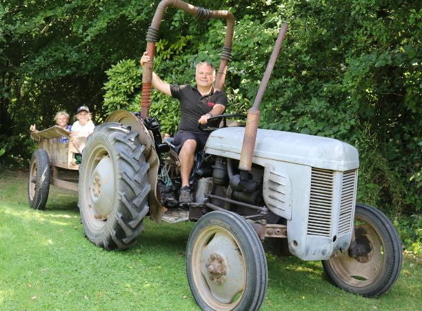 Man and two kids sitting on an old tractor