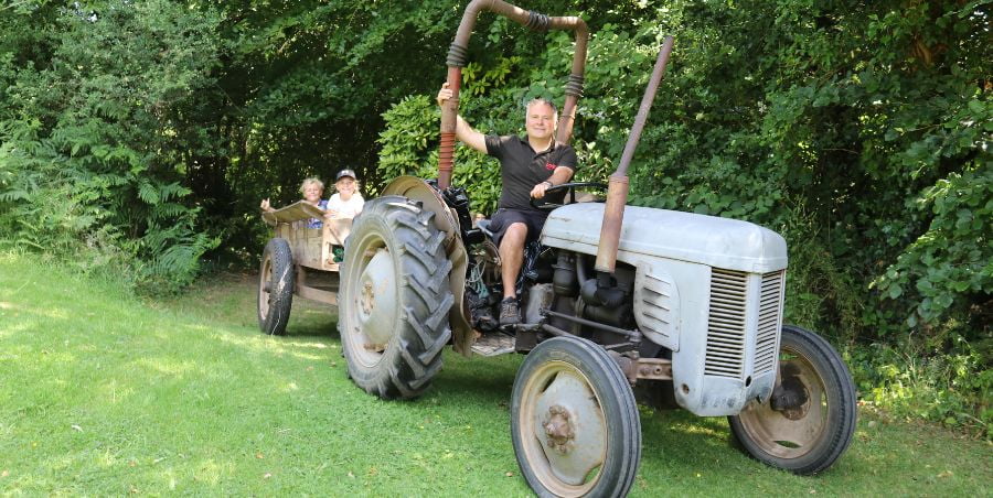 Man and two kids sitting on an old tractor