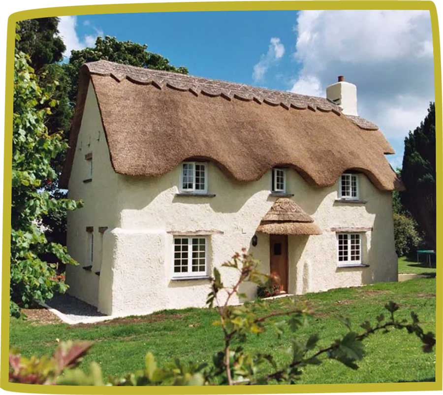 traditional thatched cottage surrounded by trees and garden