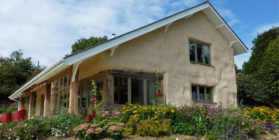 Exterior photo of large eco house with wild flowers in the fore ground