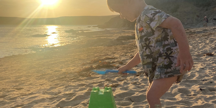 Toddler on beach building sandcastles while the sunsets